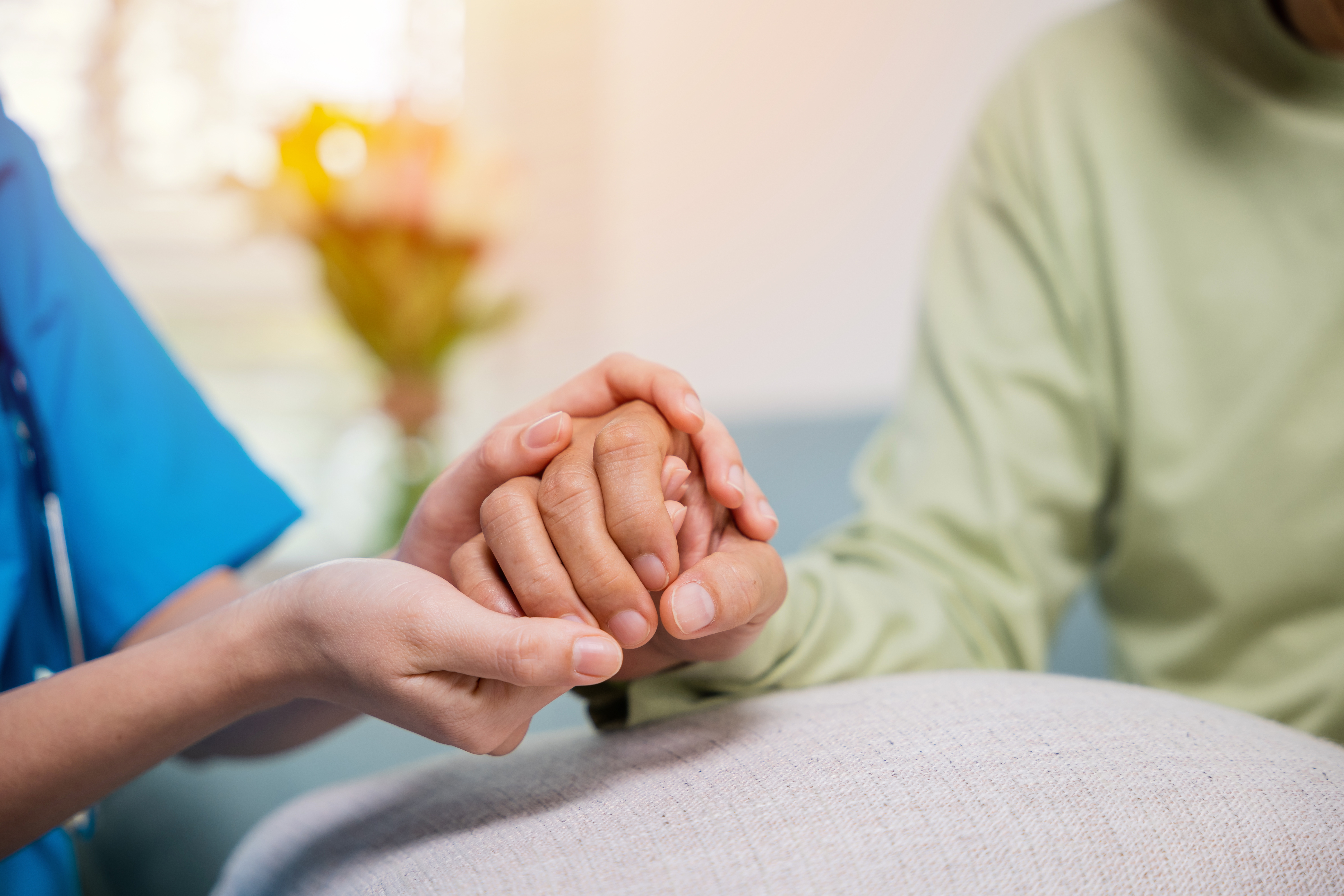 Caregiver holding patient's hand with compassion